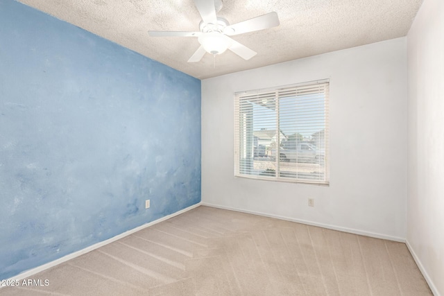 carpeted spare room with baseboards, ceiling fan, and a textured ceiling
