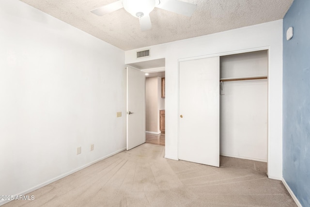 unfurnished bedroom with a closet, carpet, visible vents, a ceiling fan, and a textured ceiling