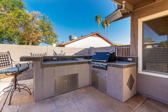 view of patio with a fenced backyard, grilling area, and exterior kitchen