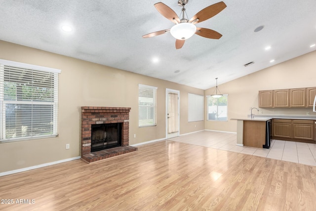 unfurnished living room with a fireplace, ceiling fan, baseboards, and light wood-style floors