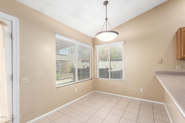 unfurnished dining area featuring lofted ceiling, a textured ceiling, light tile patterned floors, and baseboards