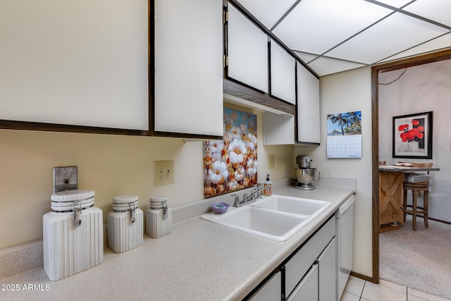 kitchen with dishwasher, white cabinetry, sink, and light carpet