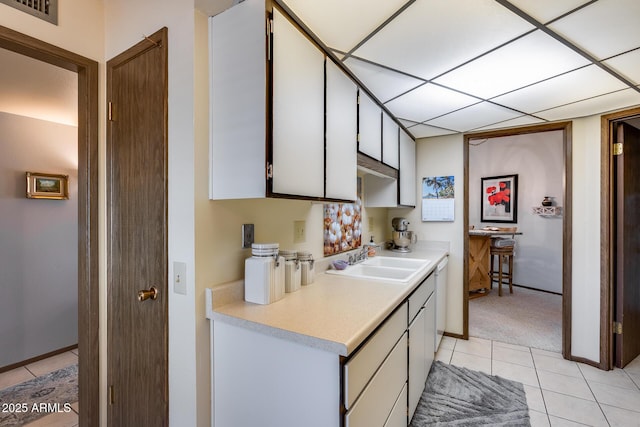 kitchen featuring white cabinetry, sink, light tile patterned floors, and white dishwasher