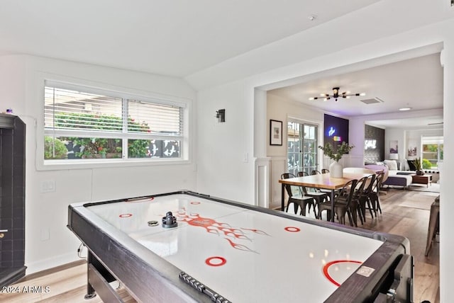 recreation room featuring a healthy amount of sunlight, vaulted ceiling, and light hardwood / wood-style flooring