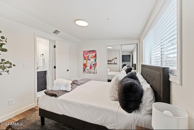 bedroom featuring ensuite bathroom, a closet, vaulted ceiling, and hardwood / wood-style flooring