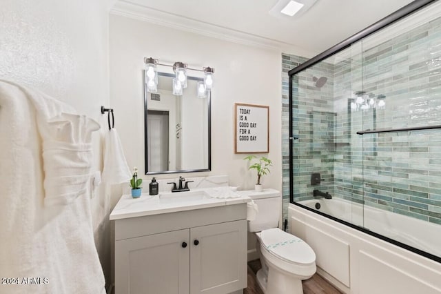 full bathroom featuring hardwood / wood-style floors, vanity, combined bath / shower with glass door, toilet, and ornamental molding