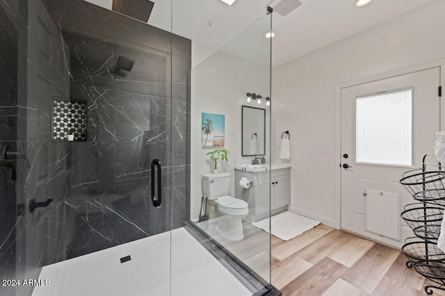 bathroom featuring wood-type flooring, vanity, toilet, and a shower with shower door