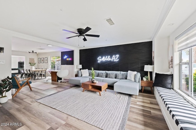 living room with light hardwood / wood-style floors, ceiling fan, and crown molding