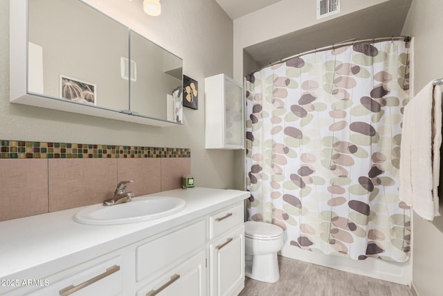 bathroom with visible vents, backsplash, toilet, vanity, and wood finished floors