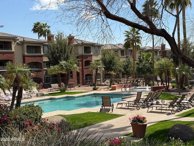 community pool with a patio area and fence