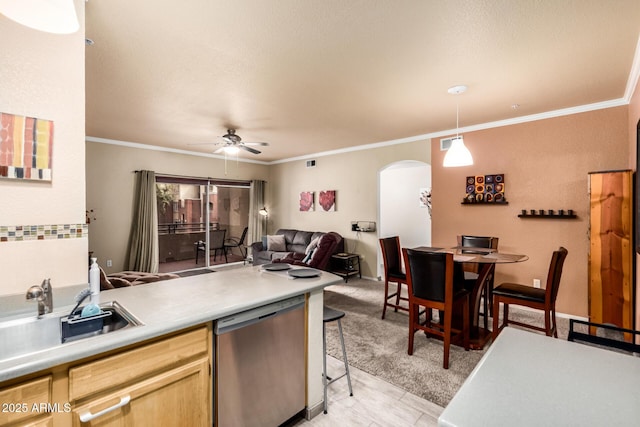 kitchen featuring dishwasher, a sink, arched walkways, and crown molding