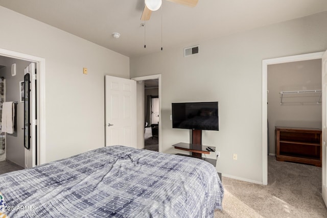 carpeted bedroom featuring a walk in closet, a closet, visible vents, a ceiling fan, and baseboards