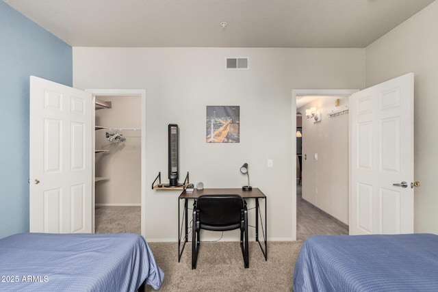 carpeted bedroom featuring a spacious closet, visible vents, and baseboards