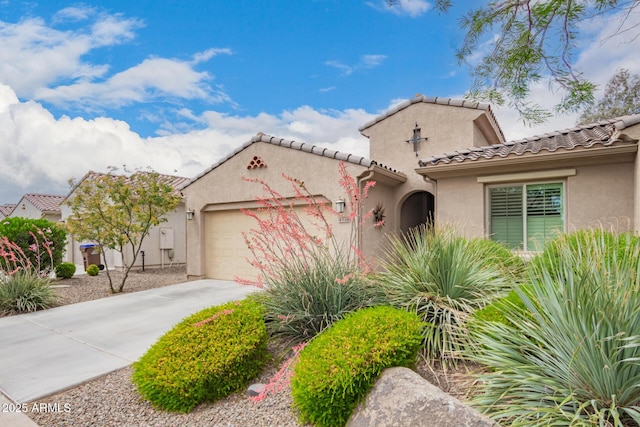 mediterranean / spanish home featuring an attached garage, stucco siding, a tiled roof, and concrete driveway