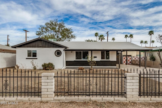 ranch-style house featuring a carport, brick siding, a fenced front yard, and concrete driveway