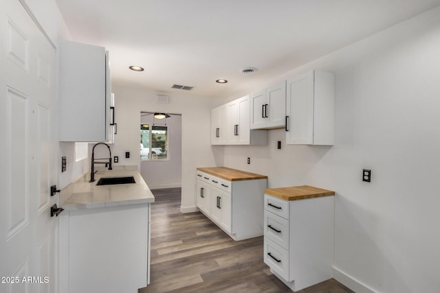 kitchen featuring wood counters, visible vents, a sink, and wood finished floors