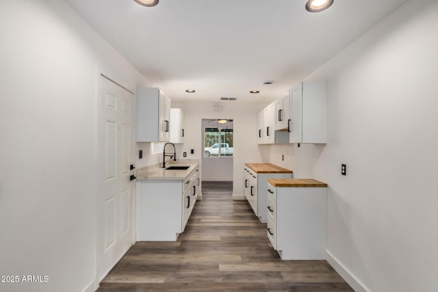 kitchen with dark wood finished floors, butcher block counters, a sink, and recessed lighting