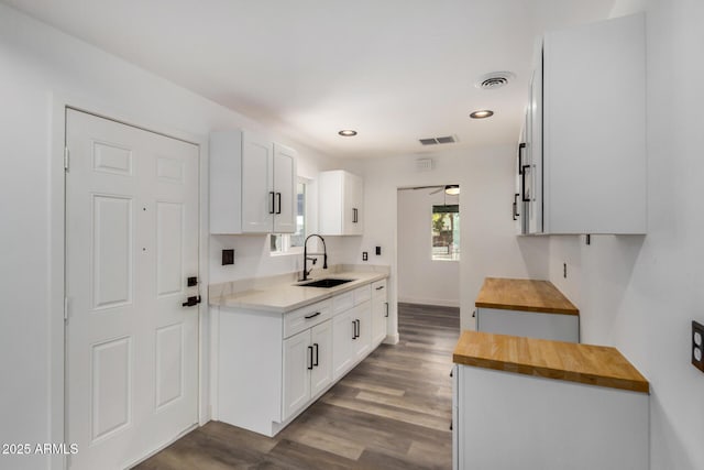 kitchen with dark wood-type flooring, visible vents, wooden counters, and a sink