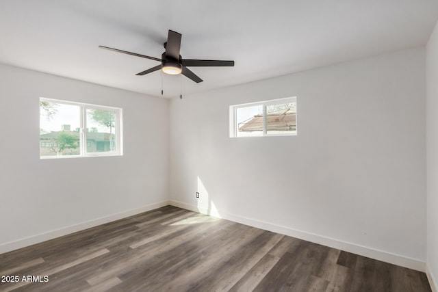 unfurnished room with dark wood-type flooring, plenty of natural light, and baseboards