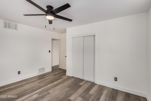 unfurnished bedroom featuring baseboards, visible vents, and wood finished floors