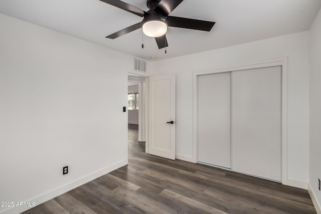 unfurnished bedroom with baseboards, visible vents, a ceiling fan, dark wood-style flooring, and a closet