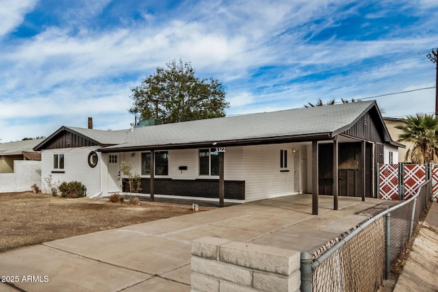 single story home with a carport, concrete driveway, and fence