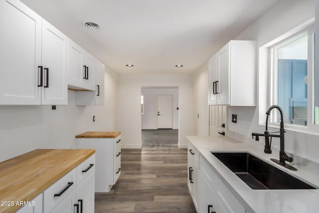 kitchen with butcher block countertops, wood finished floors, a sink, visible vents, and a healthy amount of sunlight