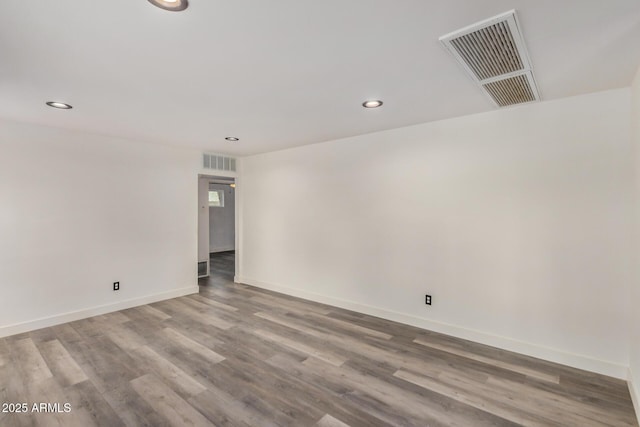 spare room with baseboards, visible vents, wood finished floors, and recessed lighting