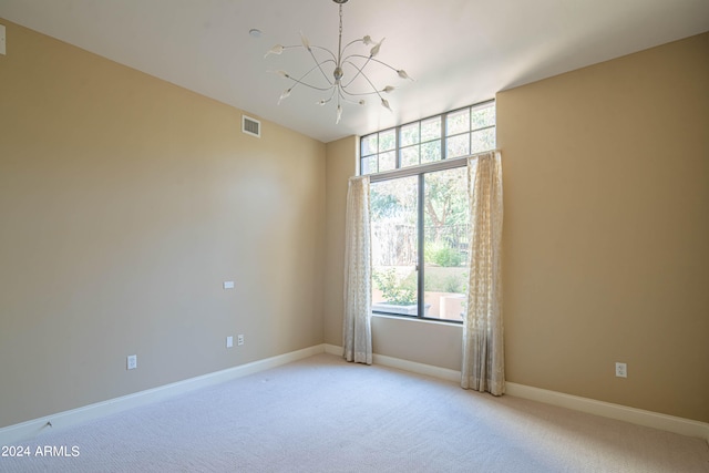 carpeted spare room featuring an inviting chandelier and a wealth of natural light