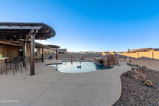 view of pool with pool water feature, exterior bar, and a patio