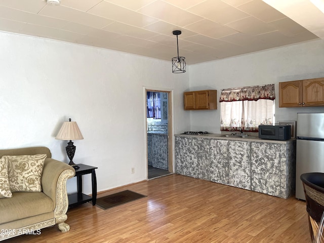 kitchen with stainless steel fridge, sink, wood-type flooring, and decorative light fixtures