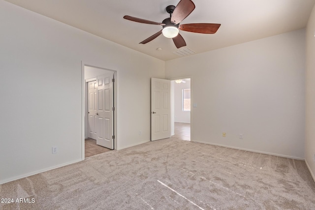 unfurnished bedroom with connected bathroom, light colored carpet, and ceiling fan