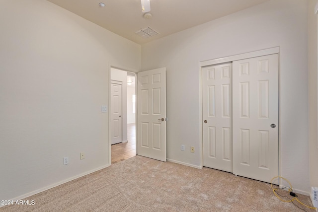 unfurnished bedroom featuring light colored carpet and a closet