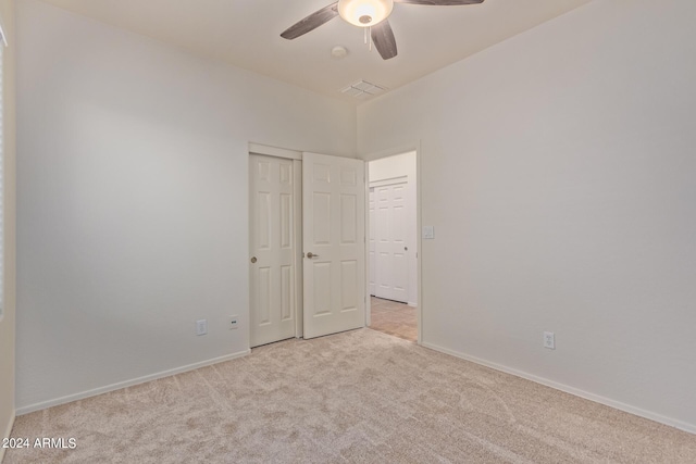 unfurnished bedroom with light carpet, a closet, and ceiling fan