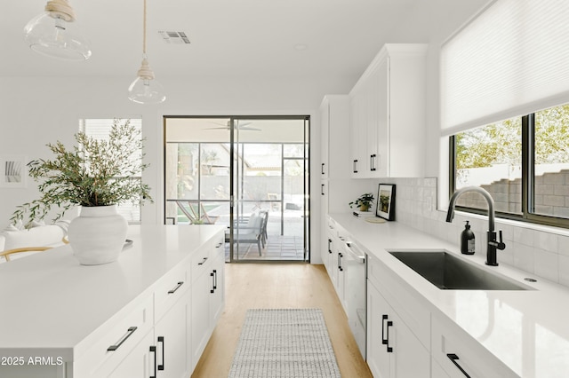 kitchen featuring sink, decorative light fixtures, and white cabinets