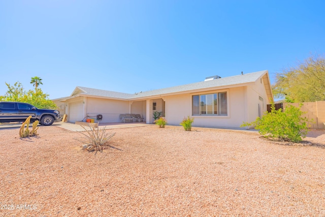 ranch-style home with a garage, fence, and stucco siding