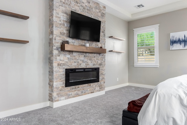 carpeted living room featuring a stone fireplace