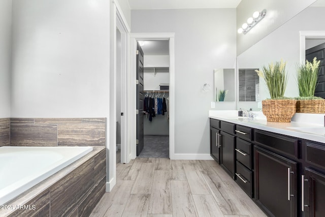 bathroom with vanity, tiled bath, and hardwood / wood-style floors