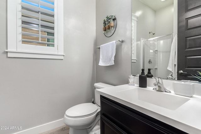 bathroom featuring a shower with door, vanity, and toilet