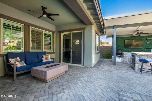 view of patio featuring an outdoor living space with a fire pit, ceiling fan, and exterior kitchen