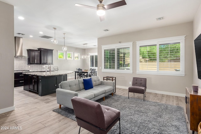 living room with a wealth of natural light, ceiling fan, and light wood-type flooring