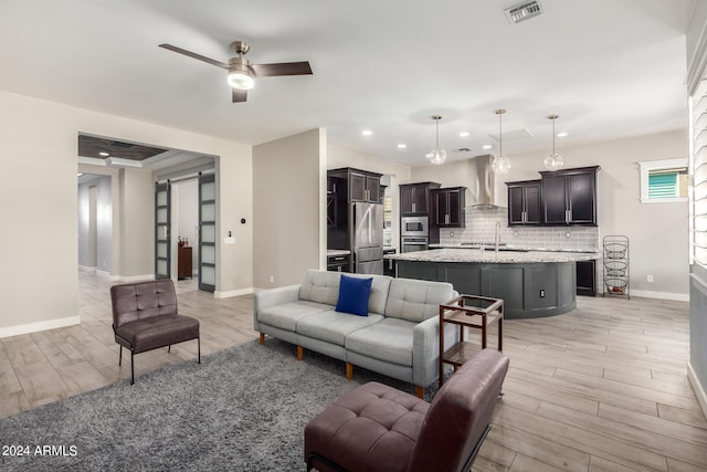 living room with sink, ceiling fan, and light hardwood / wood-style floors