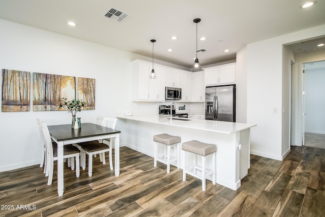 4063 E Amoroso Dr, Gilbert, AZ 85296 - kitchen with stainless steel appliances, dark wood-style flooring, a peninsula, recessed lighting, and light countertops