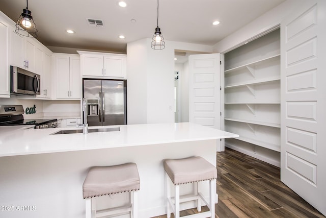 4063 E Amoroso Dr, Gilbert, AZ 85296 - kitchen featuring appliances with stainless steel finishes, a breakfast bar area, dark wood-style floors, a peninsula, and light countertops