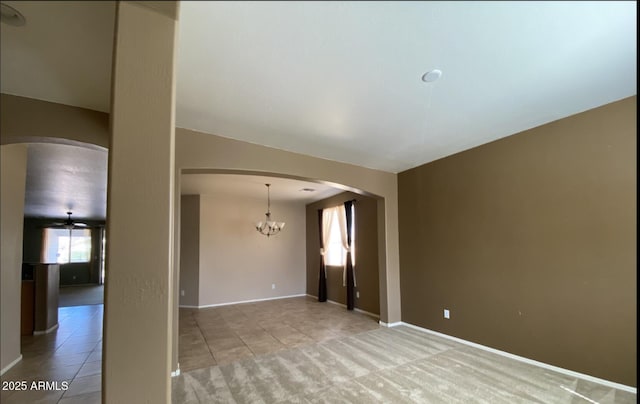 tiled empty room featuring ceiling fan with notable chandelier