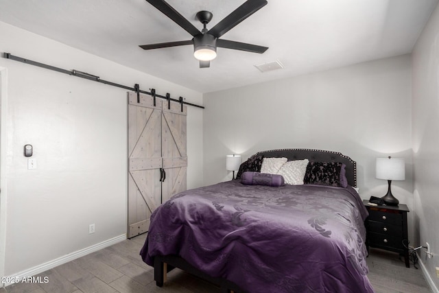 bedroom with ceiling fan, hardwood / wood-style floors, and a barn door