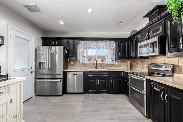 kitchen with light wood-type flooring, stainless steel appliances, tasteful backsplash, and sink