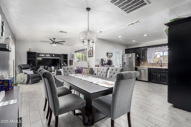 dining space with ceiling fan with notable chandelier and sink