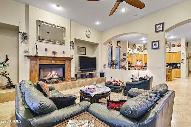 tiled living room with a high end fireplace and ceiling fan with notable chandelier