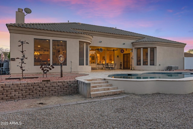 back house at dusk featuring a patio area